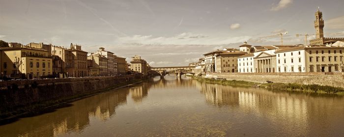 Bridge over river by buildings against sky in city