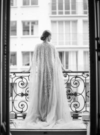 Rear view of woman standing against window