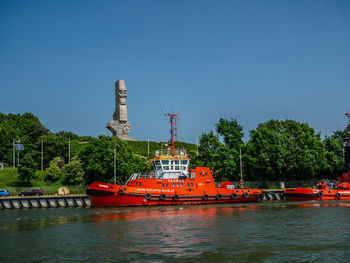 Boats in river against clear blue sky