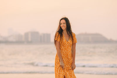 Young woman standing by water against sky