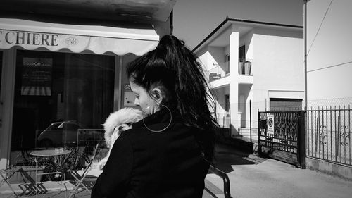 Woman looking at camera while standing against built structure