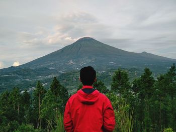 Rear view of woman looking at mountains against sky