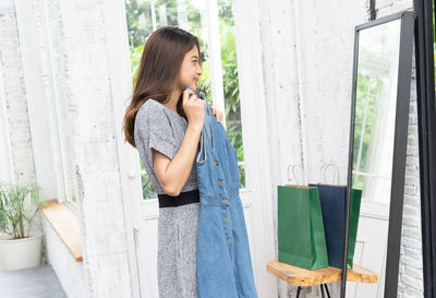 Woman looking away while standing against window