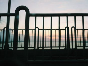 Close-up of railing against window at sunset