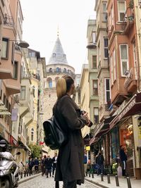 Rear view of woman walking on street amidst buildings in city