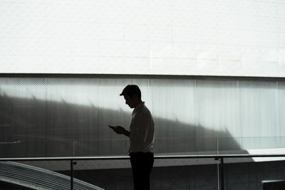 Side view of young man looking against wall