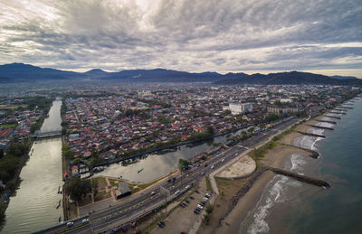 High angle view of city buildings against cloudy sky