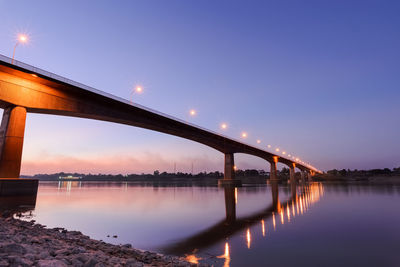 Bridge over river against sky at sunset