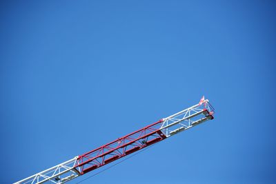 Low angle view of crane against clear blue sky