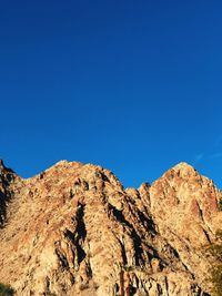 Low angle view of rock formation against clear blue sky