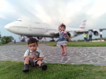 Sibling against airplane at park