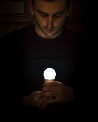 Close-up of woman holding illuminated lamp in darkroom