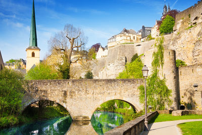 Arch bridge over canal amidst buildings against sky