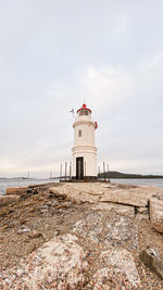 Lighthouse by sea against sky