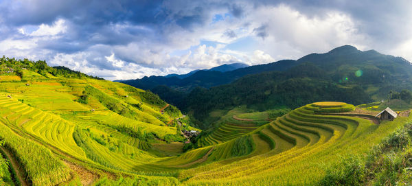 Scenic view of green landscape against cloudy sky