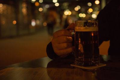 Close-up of hand holding beer glass on table