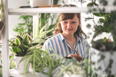 Portrait of young woman standing against plants