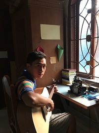 Portrait of man playing guitar at home