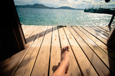 Low section of woman sitting on wooden door