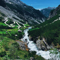 Scenic view of waterfall by mountains against sky