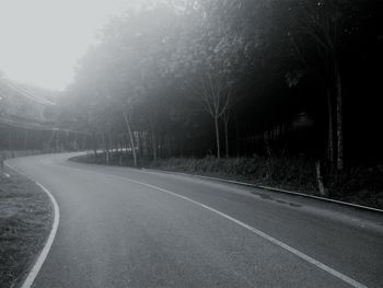 Road amidst trees against clear sky