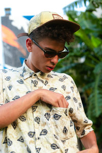 A young man checking o tshirt pocket wearing sunglasses