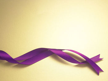 Close-up of purple ribbon over yellow background