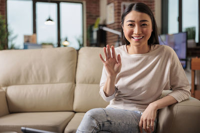 Young woman using phone while sitting on sofa at home