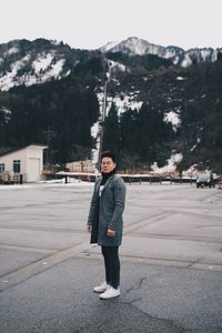 Portrait of man standing on road in winter