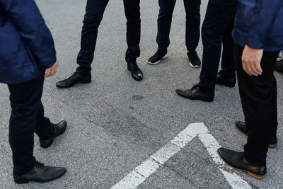 Low section of friends standing on road in city