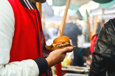 Midsection of man holding burger