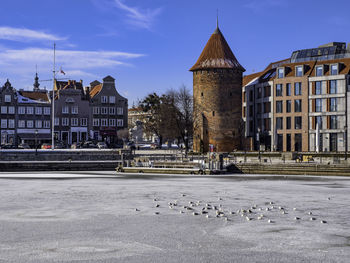 Frozen river in gdansk poland city against sky