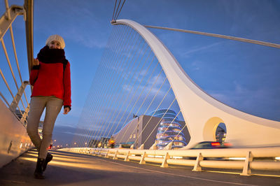 Rear view of man on bridge against sky in city