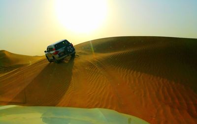 Car on landscape against sky during sunset