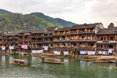 Houses by river and buildings against sky