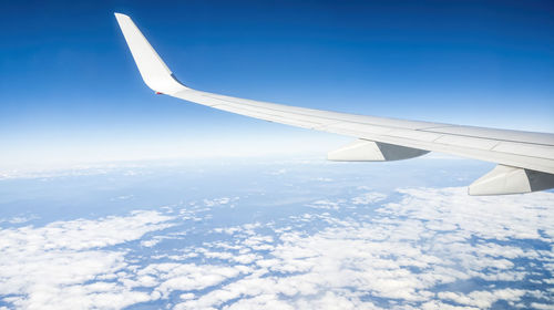 Airplane flying over snowcapped mountain against sky