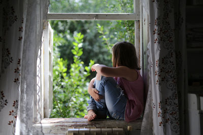 Child girl on the window, the concept of sadness and loneliness, the problems of childhood