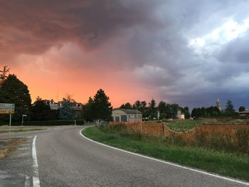 Empty road against cloudy sky at sunset