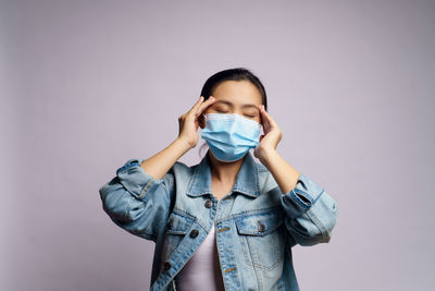 Young women wearing face mask against wall