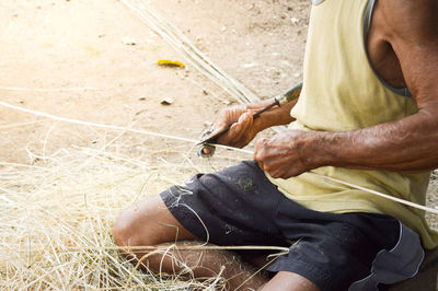 Midsection of man working on bamboo