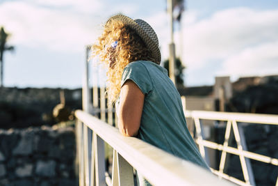 Side view of woman standing against railing