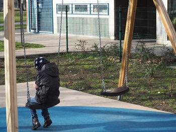 Rear view of boy sitting on swing