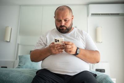 Young man using mobile phone while sitting on sofa at home