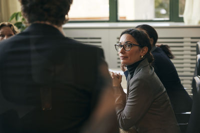 Portrait of young woman standing against wall