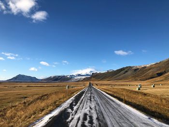 Road leading towards mountains against sky