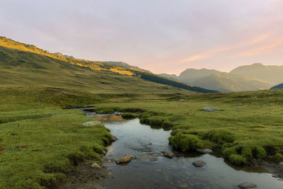 Scenic view of stream by lake against sky during sunset