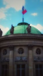 Low angle view of statue of building against cloudy sky