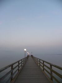 Pier over sea against sky at dusk