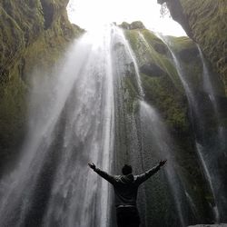 Rear view of man standing on mountain against sky