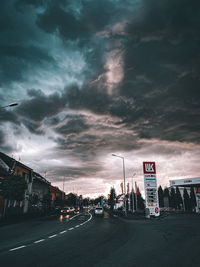 Cars on road against dramatic sky